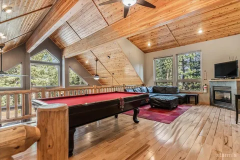 a room with furniture pool table wooden floor and windows