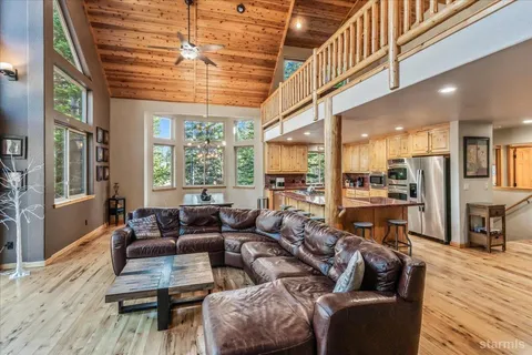 a living room with furniture wooden floor and large windows