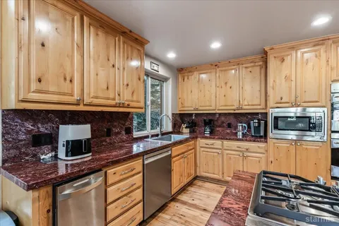 a kitchen with stainless steel appliances kitchen island granite countertop a refrigerator a stove and a sink with wooden floor