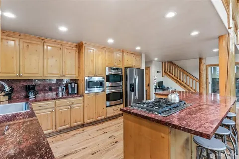 a kitchen with stainless steel appliances kitchen island granite countertop a table chairs and a refrigerator