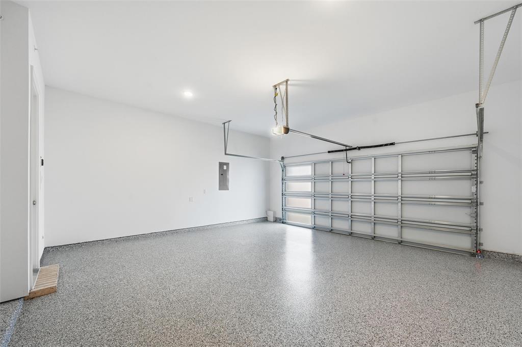 1168 Daybreak Drive, Unit 1168 Allen, TX 75013 - Photo 23 of 25 Expansive garage featuring a speckled epoxy floor, overhead lighting, and an automatic garage door opener