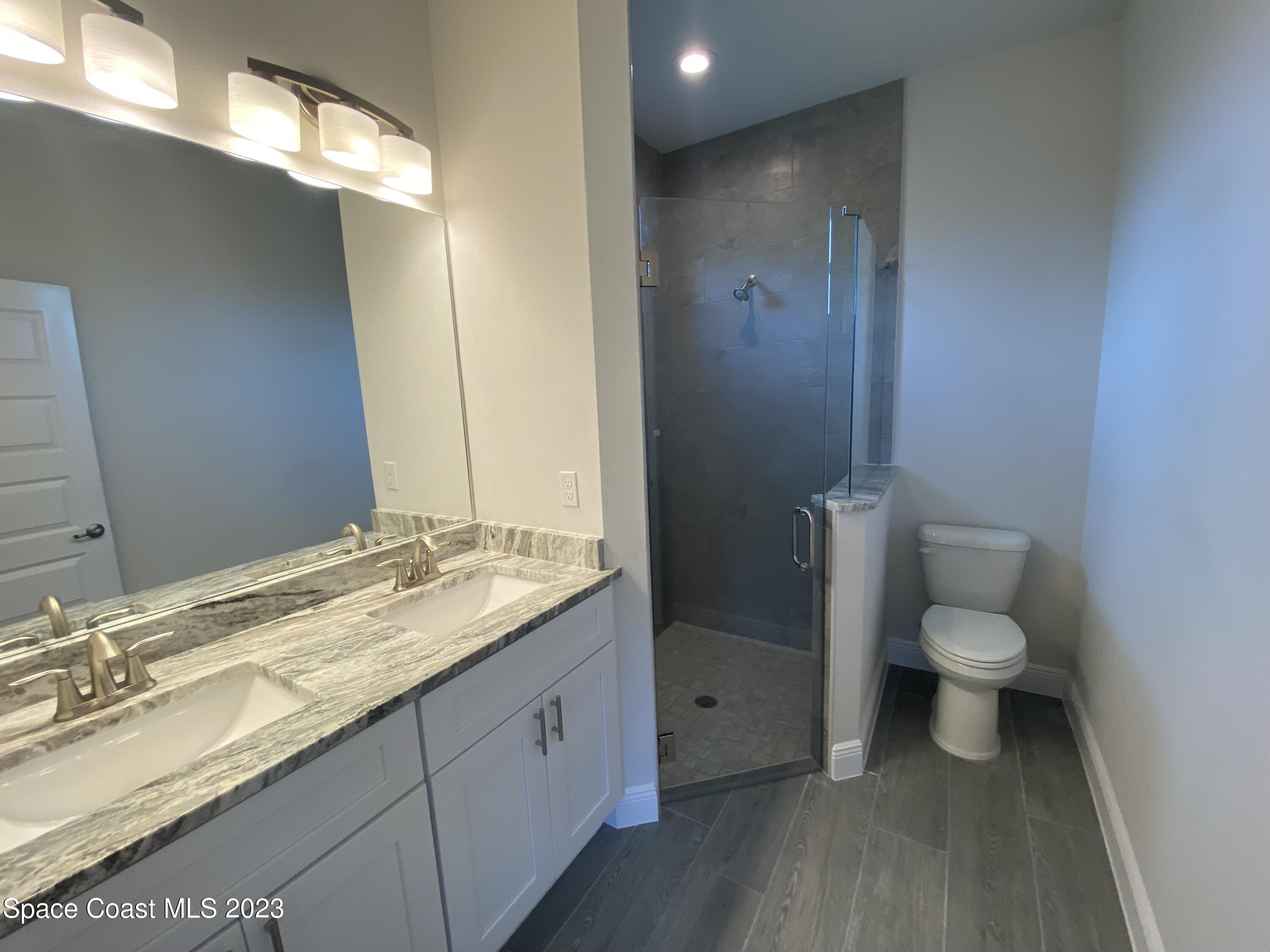 1295 Ragen Road Southeast Palm Bay, FL 32909 - Photo 3 of 44 a bathroom with a granite countertop sink toilet and shower