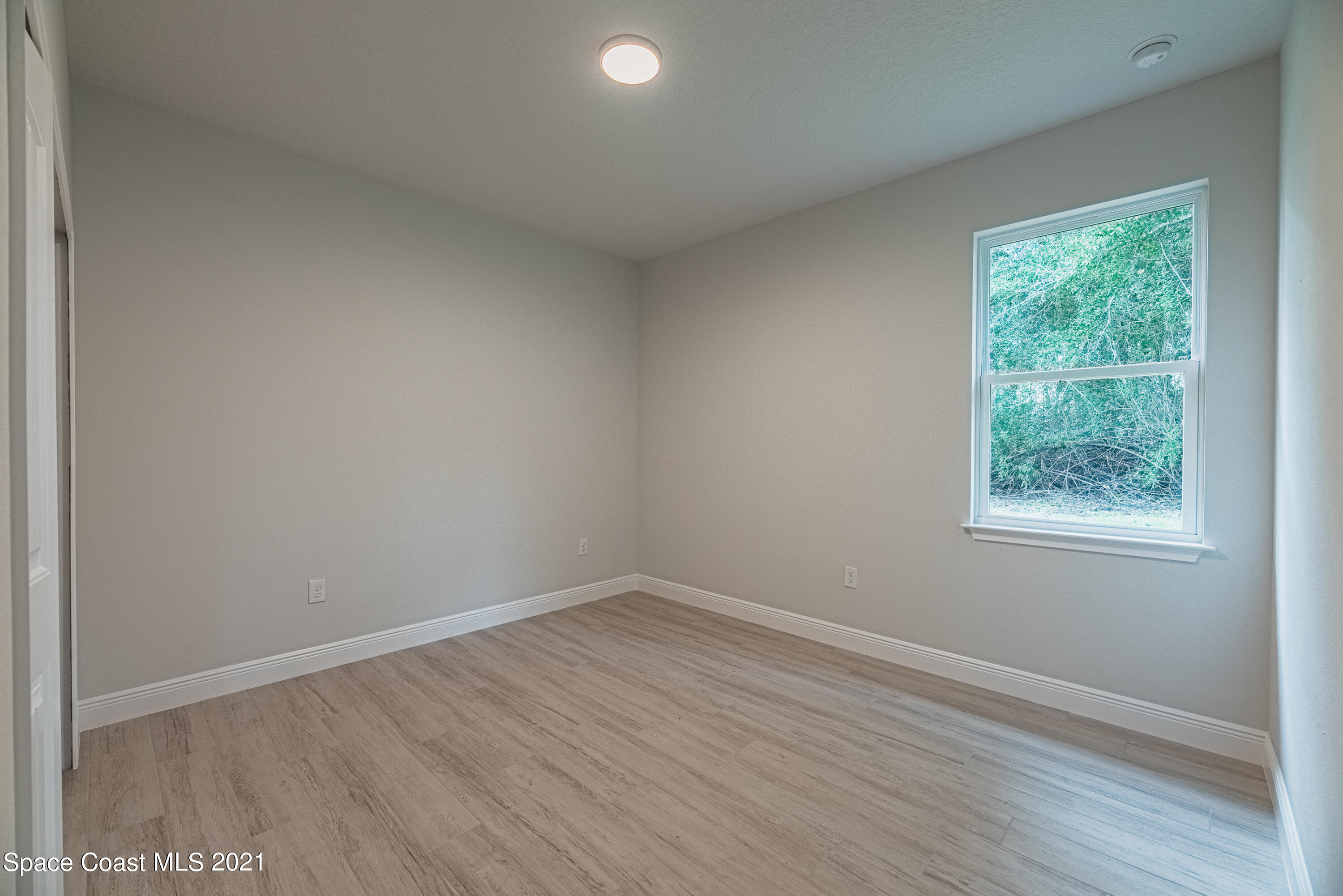 1295 Ragen Road Southeast Palm Bay, FL 32909 - Photo 32 of 44 an empty room with wooden floor and windows
