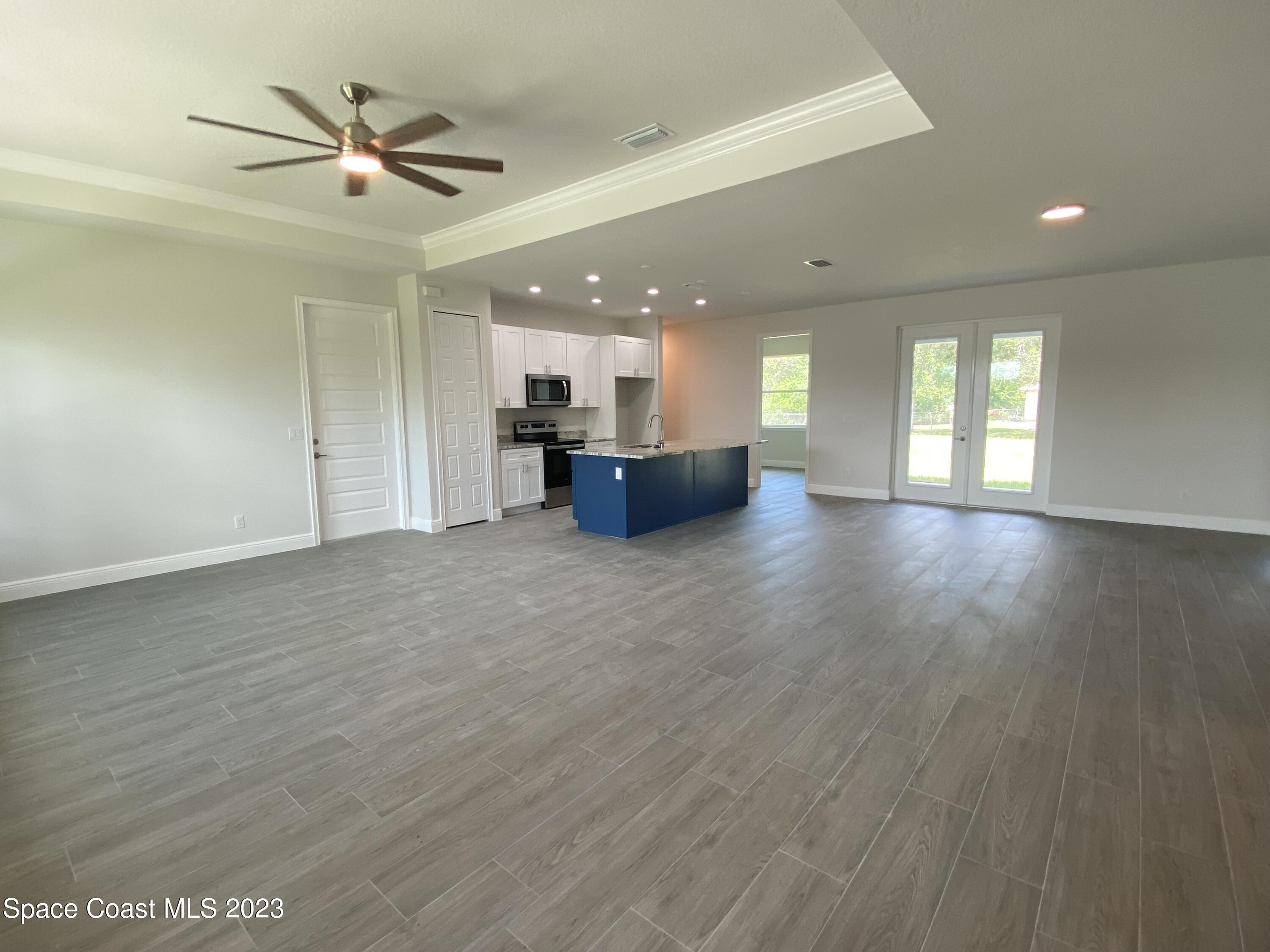 1295 Ragen Road Southeast Palm Bay, FL 32909 - Photo 5 of 44 an empty room with wooden floor and a ceiling fan