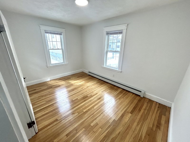 119 Bailey Road, Unit 1 Somerville, MA 02145 - Photo 13 of 25 a view of an empty room with wooden floor and a window