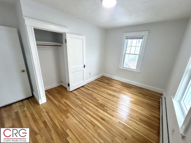 119 Bailey Road, Unit 1 Somerville, MA 02145 - Photo 14 of 25 a view of an empty room with wooden floor and a window