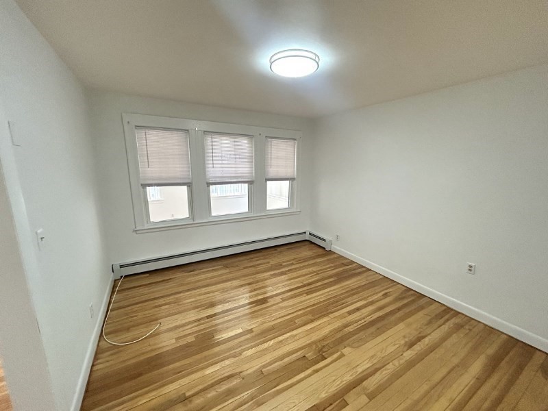 119 Bailey Road, Unit 1 Somerville, MA 02145 - Photo 3 of 25 a view of empty room with wooden floor and fan