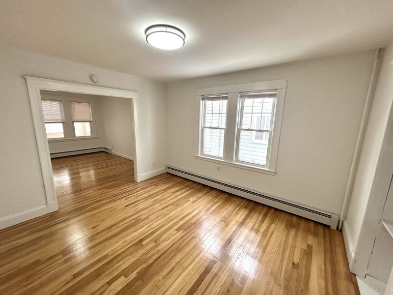 119 Bailey Road, Unit 1 Somerville, MA 02145 - Photo 6 of 25 an empty room with wooden floor and windows