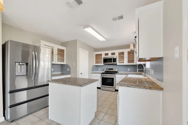 a kitchen with stainless steel appliances granite countertop a stove top oven a sink and a refrigerator