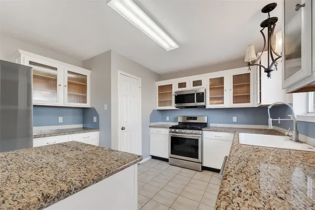 a kitchen with white cabinets and refrigerator