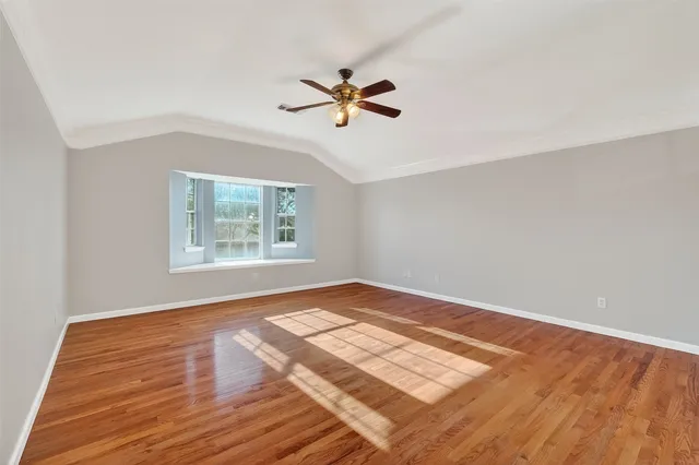 a view of a room with wooden floor and ceiling fan