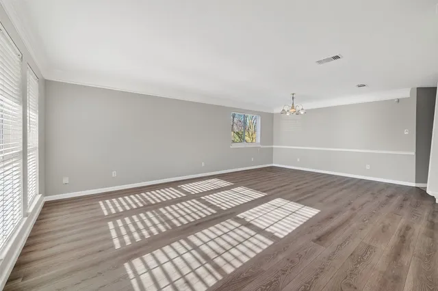 a view of an empty room with wooden floor and a ceiling fan
