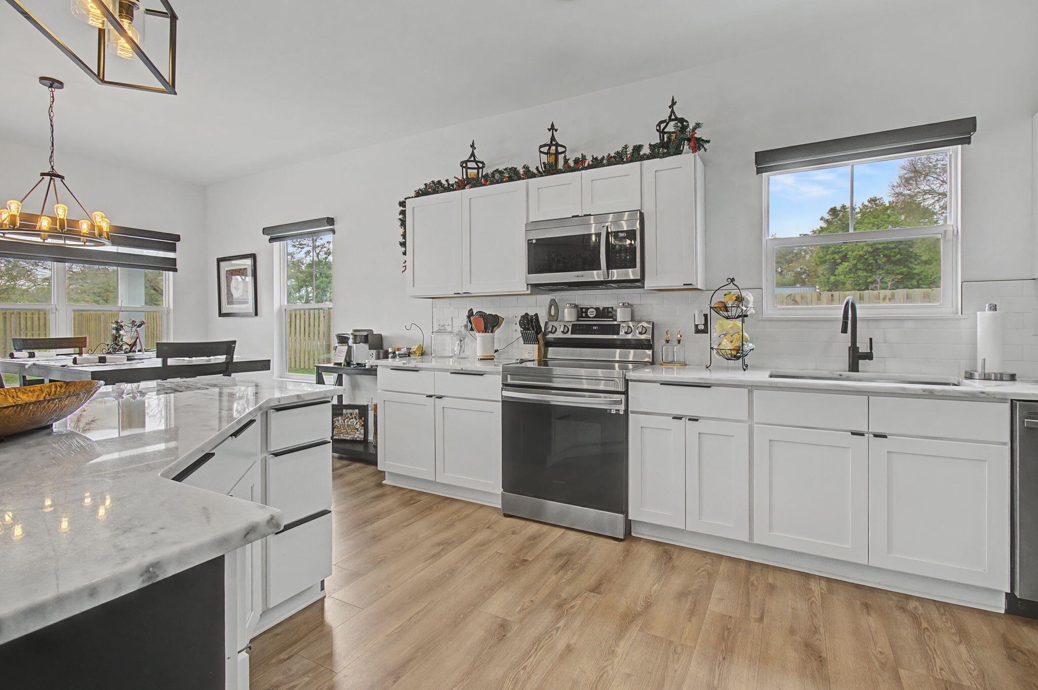 197 West 1st Avenue Crestview, FL 32536 - Photo 11 of 32 a kitchen with stainless steel appliances granite countertop a sink dishwasher stove and white cabinets with wooden floor