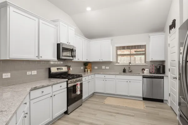 a kitchen with stainless steel appliances granite countertop white cabinets granite counter tops and a window