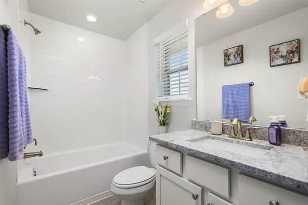 a bathroom with a granite countertop sink a toilet and shower