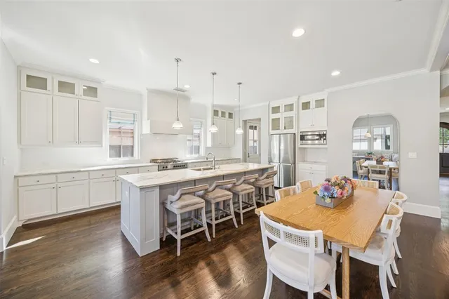 a kitchen with stainless steel appliances granite countertop a dining table chairs and sink