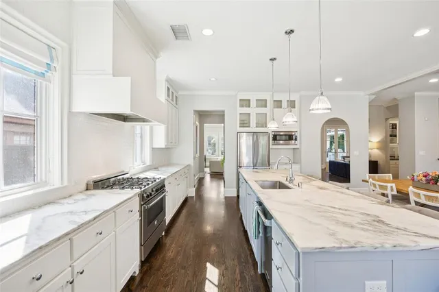 a large kitchen with granite countertop a large stove top oven a sink a counter space and stainless steel appliances