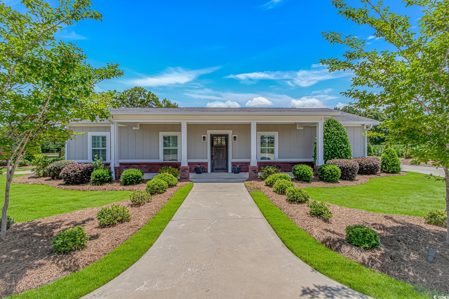View of front of house with covered porch, a front yard, brick siding, a shingled roof, and board and batten siding