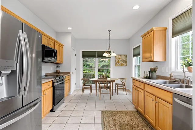 a kitchen with stainless steel appliances granite countertop a stove top oven a sink dishwasher a refrigerator and a dining table with granite countertop cabinets