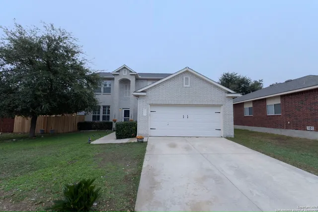 a view of a house with a yard and large tree