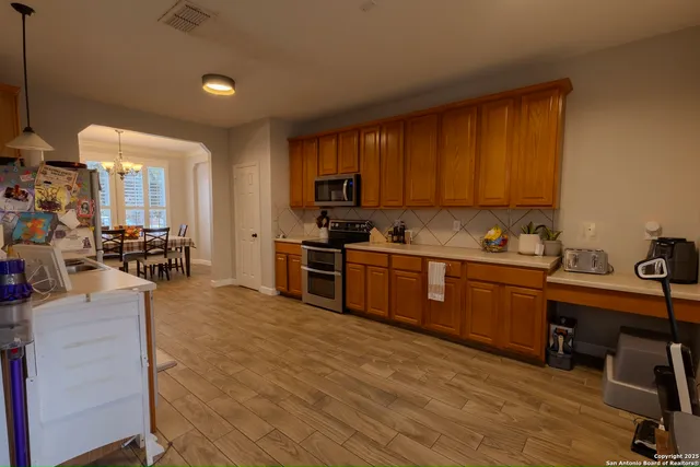 a kitchen with stainless steel appliances wooden cabinets a stove top oven a sink and dishwasher with wooden floor
