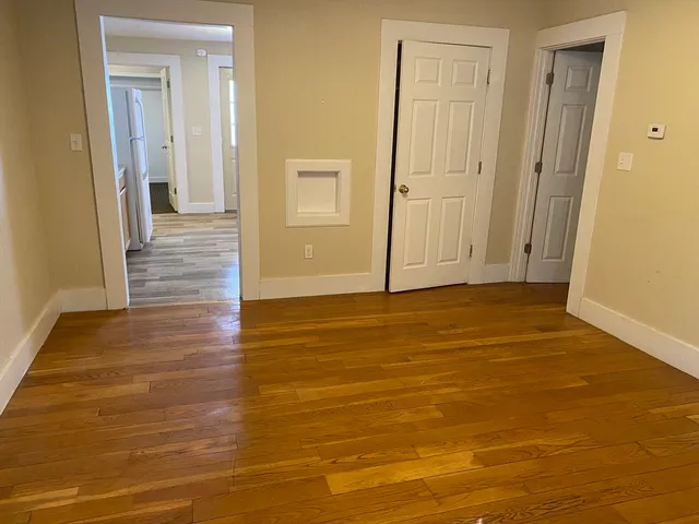 a view of a hallway with wooden floor and bathroom space