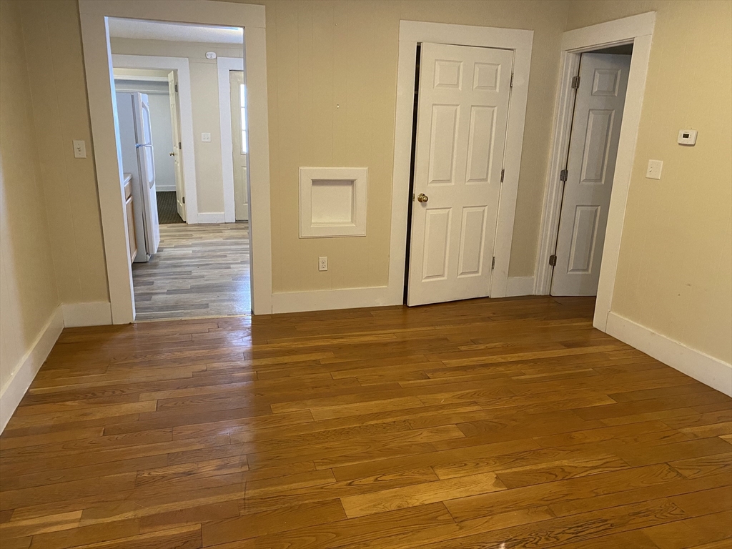 a view of a hallway with wooden floor and bathroom space