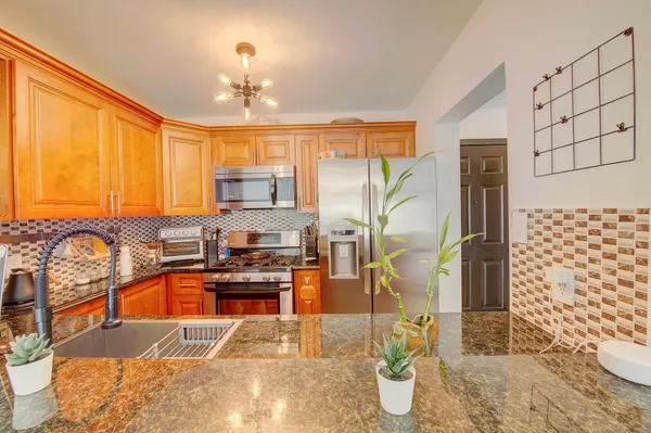 a kitchen with granite countertop a refrigerator a stove a sink dishwasher and wooden cabinets