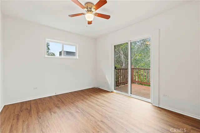 an empty room with wooden floor fan and windows