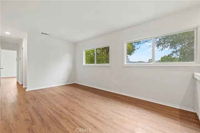 a view of empty room with wooden floor and fan