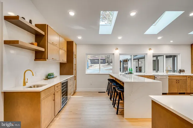 a large white kitchen with sink refrigerator and large window