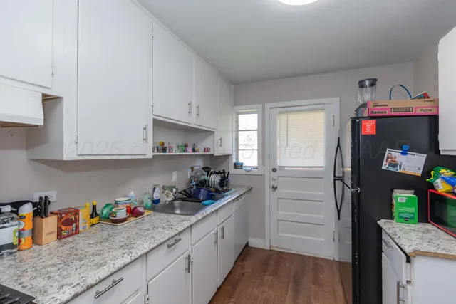 a kitchen with granite countertop a sink dishwasher stove and cabinets