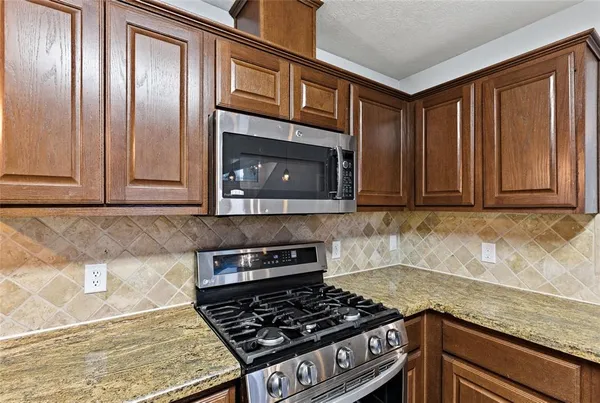 a kitchen with granite countertop stainless steel appliances a stove a sink and a microwave
