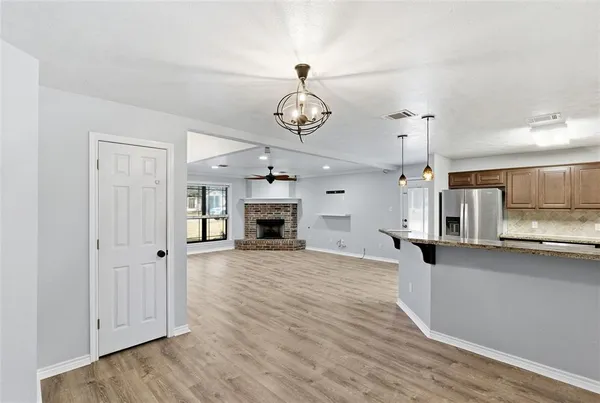 a view of a kitchen with a sink a refrigerator a fireplace and wooden floor