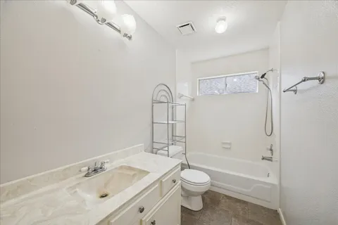 a bathroom with a bathtub shower sink vanity mirror and toilet