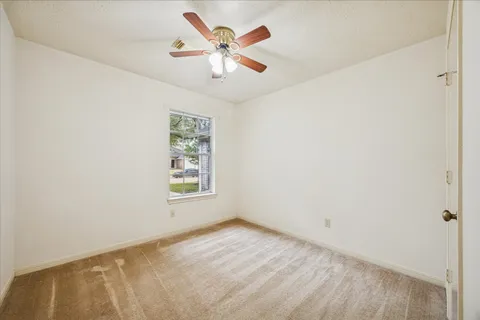an empty room with a window and a ceiling fan