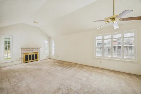 an empty room with chandelier fan and windows