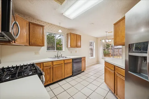 a large kitchen with stainless steel appliances a stove a sink a microwave and cabinets