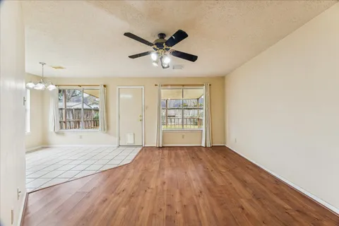 a view of an empty room with a window and wooden floor