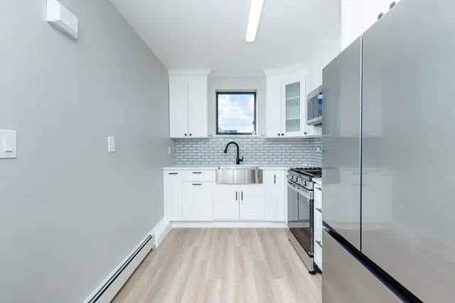 a kitchen with white cabinets stainless steel appliances and sink