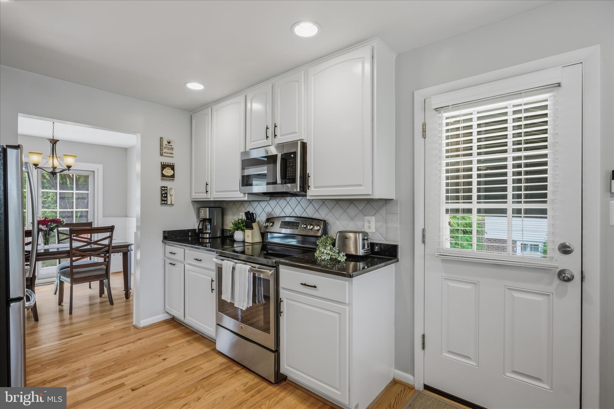 3204 Llewellyn Field Road Olney, MD 20832 - Photo 12 of 42 a kitchen with stainless steel appliances granite countertop white cabinets a sink a stove a dining table and chairs