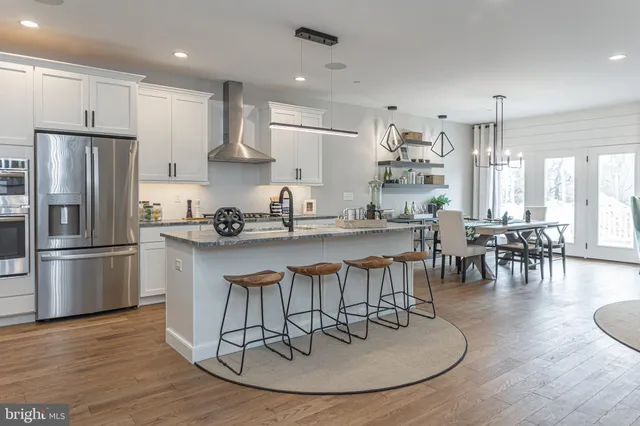 a kitchen with stainless steel appliances granite countertop a table chairs refrigerator and sink