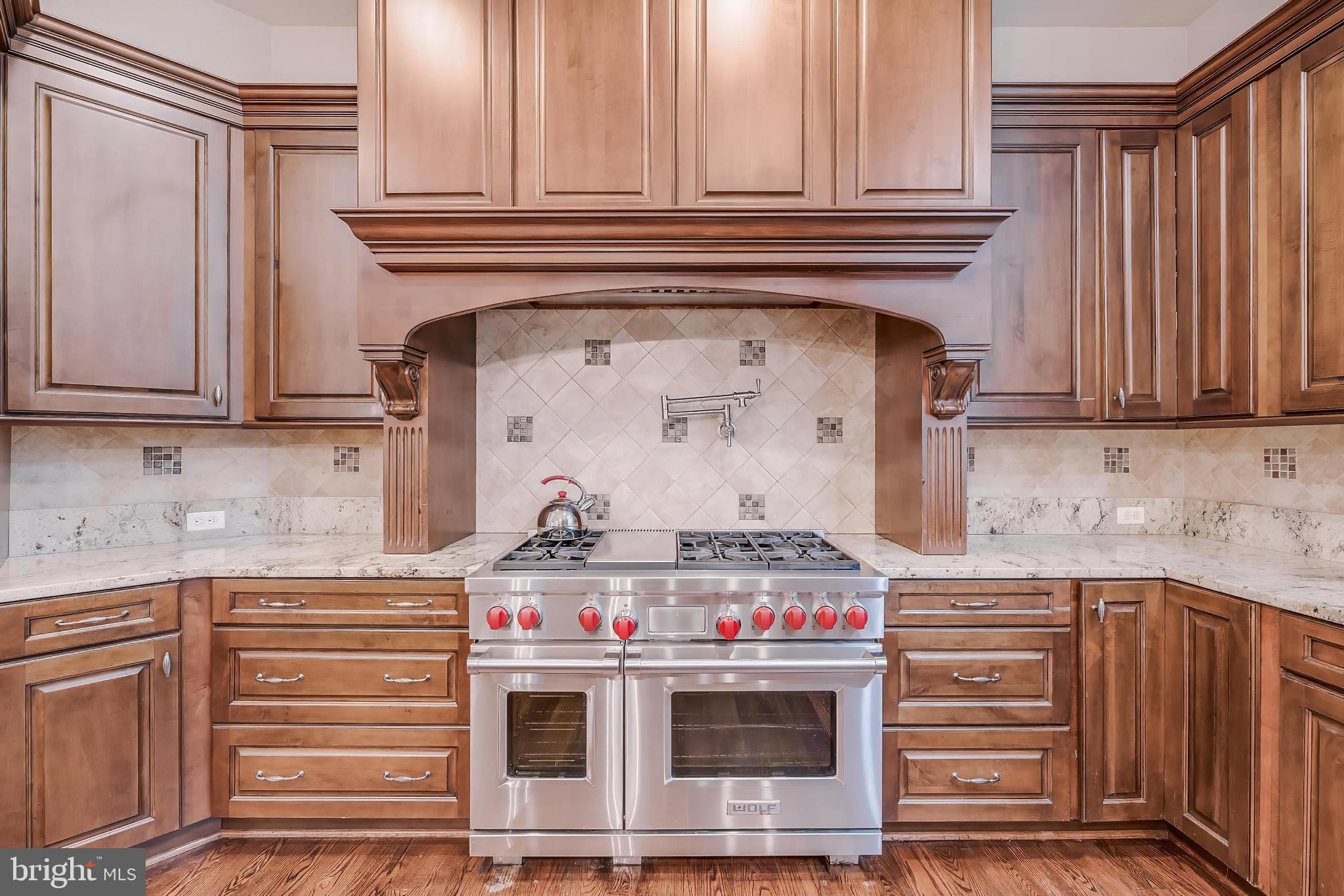 7020 Mountain Gate Drive Bethesda, MD 20817 - Photo 13 of 42 a stove top oven sitting inside of a kitchen and wooden cabinets