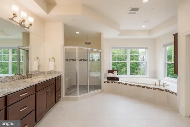 a spacious bathroom with a granite countertop tub sink shower and mirror