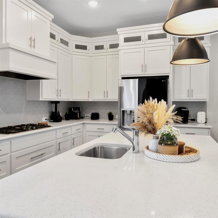 602 Winners Circle Rowlett, TX 75088 - Photo 14 of 35 Modern kitchen featuring white cabinetry, a large center island with an undermount sink, a gas cooktop, and stainless steel appliances.