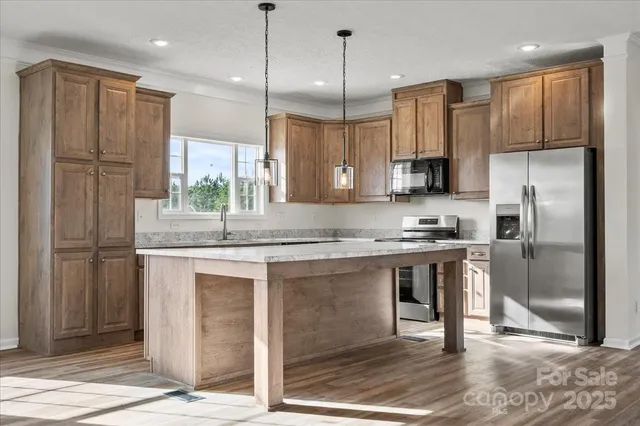 a kitchen with kitchen island granite countertop a sink appliances cabinets and a counter top space