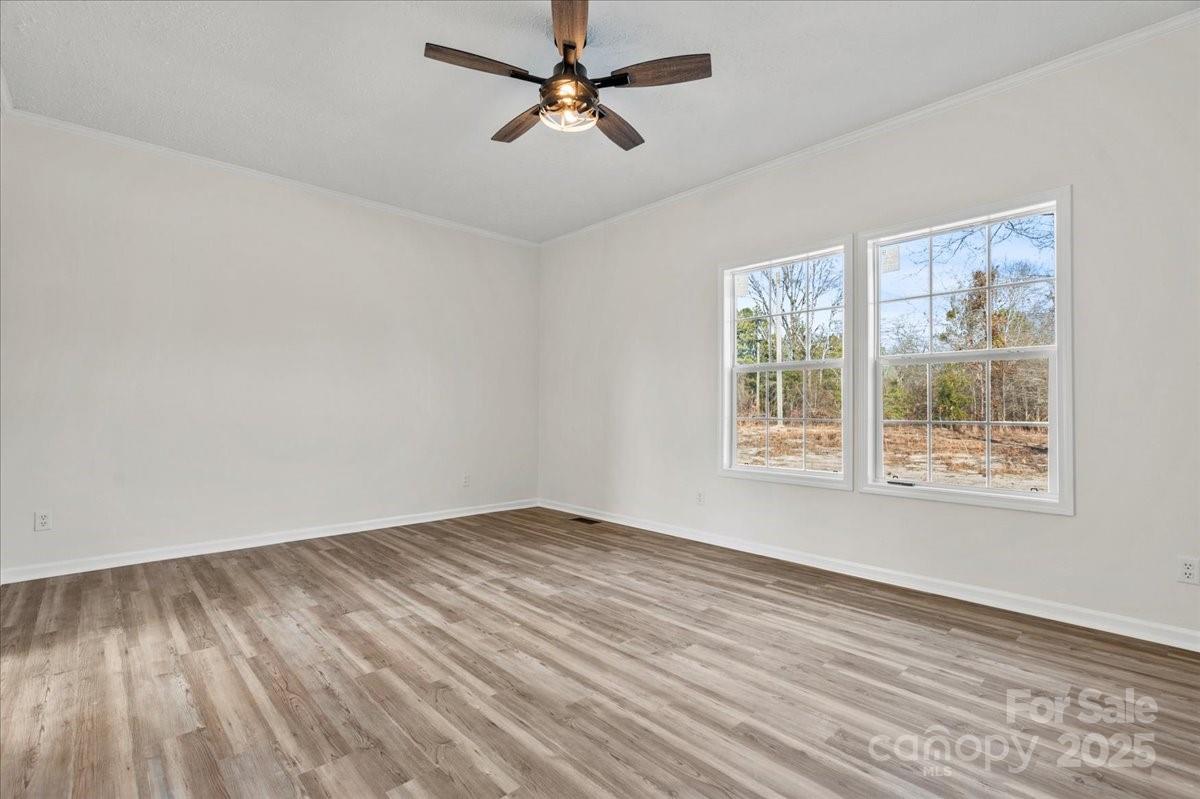 5257 Raleys Mill Road Bethune, SC 29009 - Photo 22 of 48 an empty room with wooden floor ceiling fan and windows