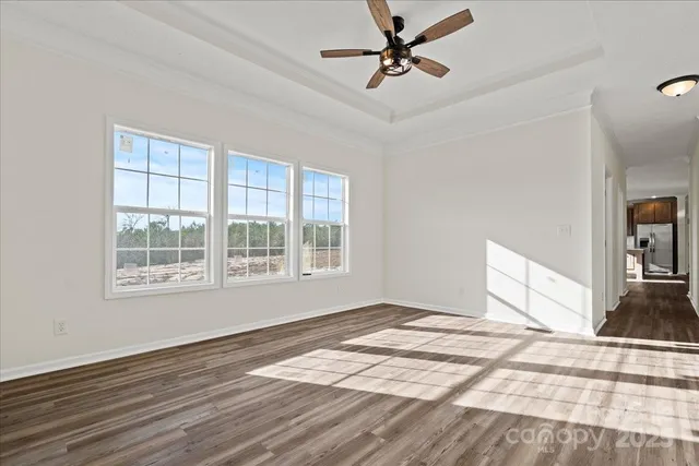 an empty room with wooden floor fan and windows