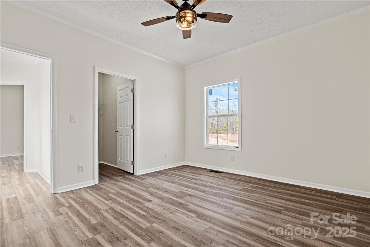 5257 Raleys Mill Road Bethune, SC 29009 - Photo 37 of 48 an empty room with wooden floor chandelier fan and windows