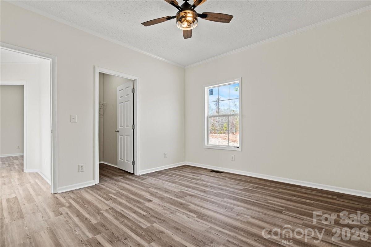 5257 Raleys Mill Road Bethune, SC 29009 - Photo 38 of 48 an empty room with wooden floor chandelier fan and windows